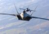 Two fighter jets flying in formation over landscape.