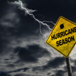 Hurricane season warning sign with lightning in stormy sky.