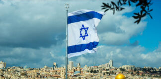 Israeli flag flying over Jerusalem skyline with Dome of Rock.