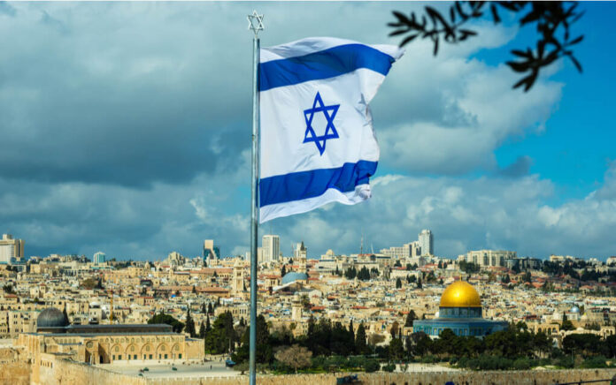 Israeli flag flying over Jerusalem skyline with Dome of Rock.