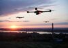 Drones flying over a landscape at sunset.