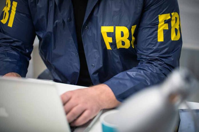 Person wearing FBI jacket working on a laptop.