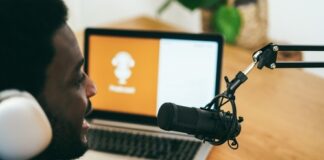 Person recording podcast with laptop and microphone.