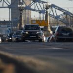 Cars driving on a road with bridge background.