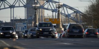 Cars driving on a road with bridge background.