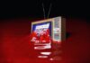 Vintage TV displaying Breaking News submerged in red liquid