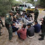 Border patrol agents detaining a group of immigrants.