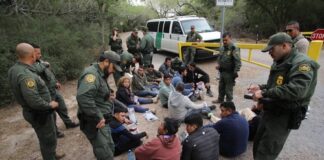 Border patrol agents detaining a group of immigrants.