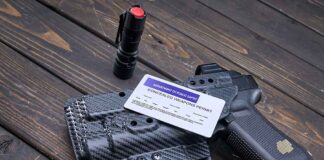 Pistol, holster, permit, flashlight, and magazine on wooden background.