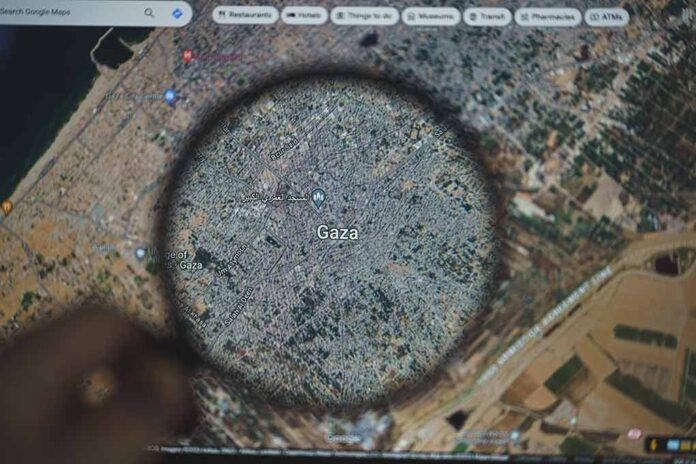 Magnifying glass over map of Gaza on a screen.