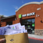 Holding tax documents outside H&R Block office.