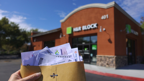 Holding tax documents outside H&R Block office.