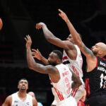 Basketball players reaching for the ball during a game.