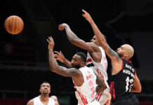 Basketball players reaching for the ball during a game.