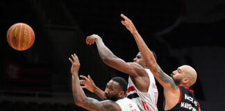 Basketball players reaching for the ball during a game.