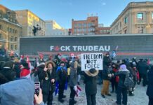 Protestors with anti-Trudeau signs in a snowy urban setting.