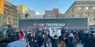 Protestors with anti-Trudeau signs in a snowy urban setting.