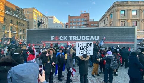 Protestors with anti-Trudeau signs in a snowy urban setting.