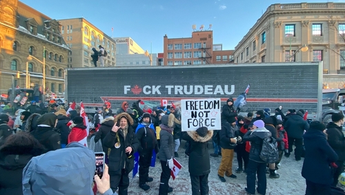 Protestors with anti-Trudeau signs in a snowy urban setting.