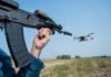 Rifle aiming at a flying drone outside on field