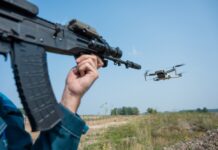 Rifle aiming at a flying drone outside on field