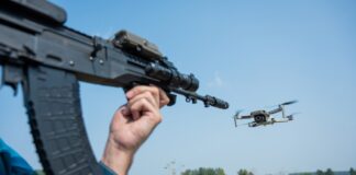 Rifle aiming at a flying drone outside on field