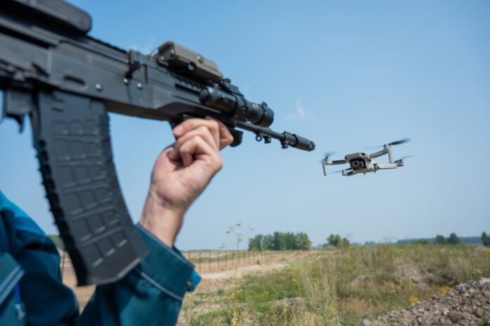 Rifle aiming at a flying drone outside on field