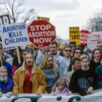 Protesters holding anti-abortion signs at a rally.