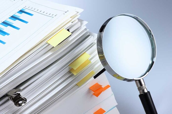 Stack of folders with a magnifying glass.