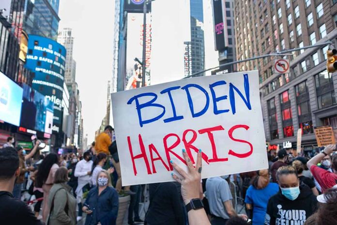 Person holding Biden Harris sign in crowded city street.