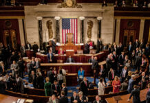 Large group in U.S. Congress chamber, American flag displayed.