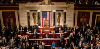 Large group in U.S. Congress chamber, American flag displayed.