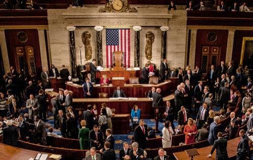 Large group in U.S. Congress chamber, American flag displayed.