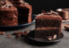 Chocolate cake slice on dark gray plate.