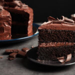 Chocolate cake slice on dark gray plate.