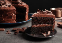 Chocolate cake slice on dark gray plate.