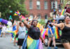 People celebrating at a pride parade, waving rainbow flags.