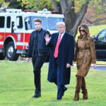 Three people walking outside near emergency vehicles