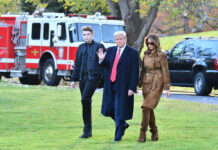 Three people walking outside near emergency vehicles