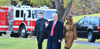 Three people walking outside near emergency vehicles