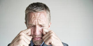 Man in suit rubbing his eyes.