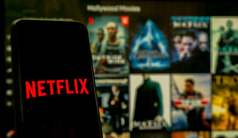 Netflix app open on phone; Hollywood movies in background.