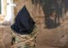 Person hooded and bound in abandoned stone room.