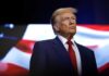 donald trump in suit with red tie American flag backdrop