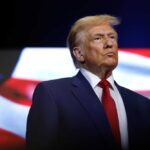 donald trump in suit with red tie American flag backdrop