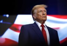 donald trump in suit with red tie American flag backdrop