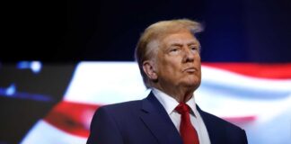 donald trump in suit with red tie American flag backdrop