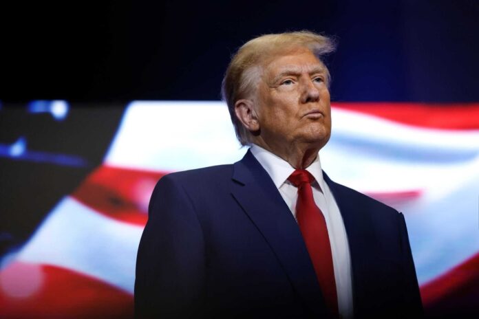 donald trump in suit with red tie American flag backdrop