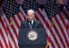 Joe Biden speaking at podium with American flags behind.