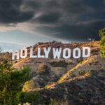 Hollywood sign on hills under cloudy sky.